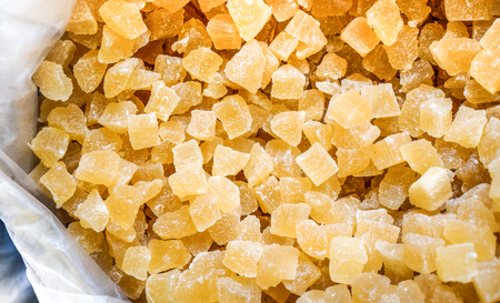 background of dried and sun dried fruits close-up shot. yellow ivory candied fruit as sweet wallpaper. sweet apple pineapple and melon dried fruit cubes as backgroundの写真素材