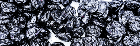many dry ripes of black plumps against white. dark blue violet dry plumps as background. Top view of prunes as background textureの写真素材