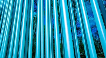 strong bright diagonal circle metal pylons against autumn forest front view, metal circle tubes...