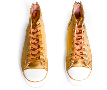 top view to golden new sneakers with white foot and wide open shoelaces on white. modern stylish sneakers isolated on white background. new high keds for woman or man stay strongの写真素材