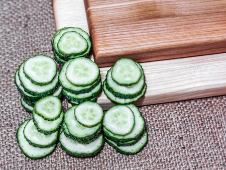 two big kitchen wooden desks with half of cucumbers. mountain of small fresh cucumbers laying on wooden desk and fabric. decoration of wooden table and cucumbers decoration on tableの写真素材