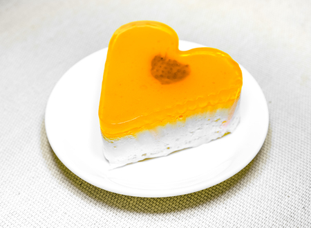 fresh yellow orange jelly heart cake with berry inside lay on round white plate. sweet jelly...