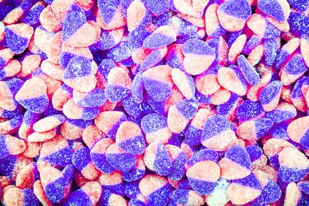 Red fruit candy in the form of the heart, strewed by sugarの写真素材