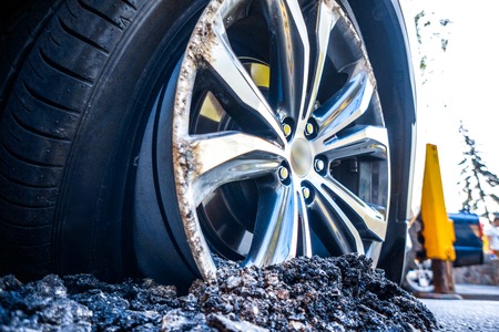 the car's drive burrowed into the asphalt as a result of car crash. silver luxury car wheel inside road asphalt after car crash. Round Damaged vehicle closeup after car crash.の写真素材