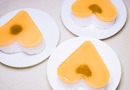 zigzag made by cakes. three sweet jelly heart cakes on white plates stand on pink table. parts of cakes on round plates. sweet jelly heart-shaped cakes on white concrete backgroundの写真素材