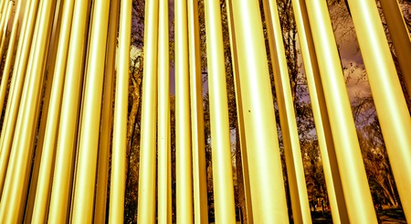 strong bright diagonal circle metal pylons against autumn forest front view, metal circle tubes...