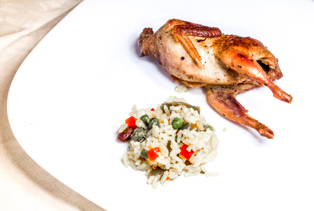 fried quail with fresh vegetables on the wooden board on green grass. Prepared tomato, cucumber, partridge, quail. Roasted Partridge, quail grilling on sunny day. Culinary concept with delicious food.の写真素材