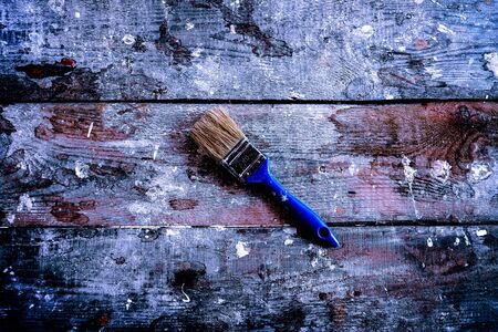 big paint brushes with big blue hand and some parts of paint against the background from an old tree with small paint spots.の写真素材