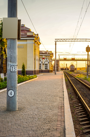 old country railroad against beautiful sky at sunset. Industrial landscape with railway station, colorful blue sky, trees and grass, yellow sunlight. Railway junction. Heavy industry. Railways.の写真素材
