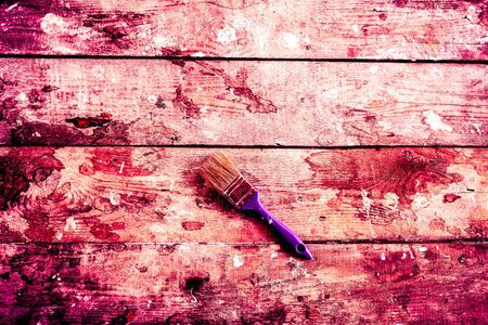 big paint brushes with big blue hand and some parts of paint against the background from an old tree with small paint spots.の写真素材