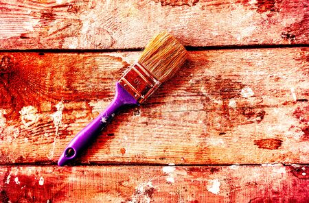 big paint brushes with big blue hand and some parts of paint against the background from an old tree with small paint spots.の写真素材