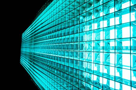 Turquoise color metal mesh with a square pattern on a bright lamp with gradient effect on a black backgroundの写真素材