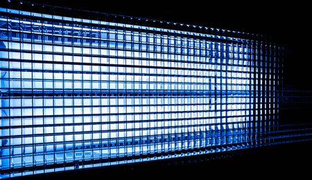 Turquoise color metal mesh with a square pattern on a bright lamp with gradient effect on a black...