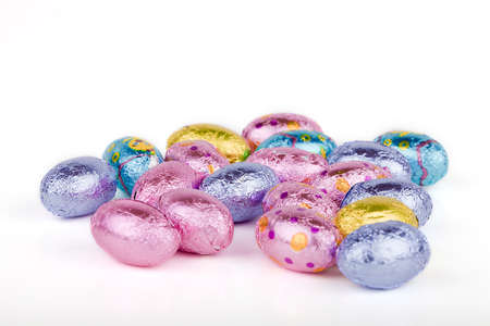 Closeup of colorful Easter eggs on a white surface. Chocolate Easter eggs isolated on white...