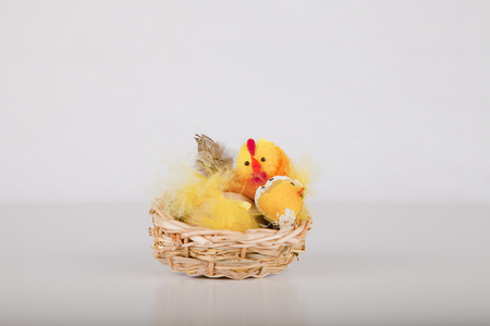 Easter chicks in a wicker basket on a white surface. Easter decoration isolated on white background.の写真素材