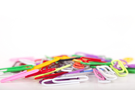 Pile of colorful paperclips on a white surface. Paperclips isolated on white background.の写真素材