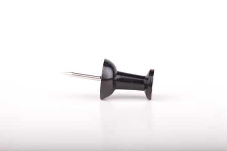 Black plastic push pin on a white surface. Black pushpin isolated on white background.の写真素材
