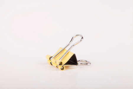 Yellow paper clip on a white surface. Yellow paperclip isolated on white background.の写真素材
