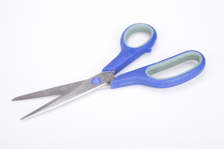 A pair of blue scissors on a white surface. Blue scissors isolated on white background.