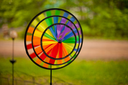Colorful triple pinwheel spinning in the wind. Round pinwheel with bright colorful ribbons on the lawn rotating with the wind. Beautiful summer decoration.の写真素材
