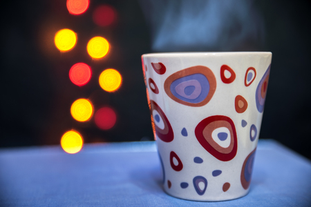 a mug of hot tea on the background of lightsの写真素材