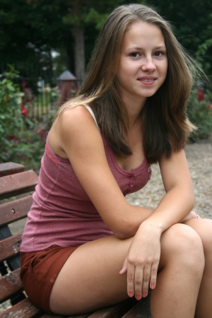 Pretty girl in rose garden seating on the benchの写真素材