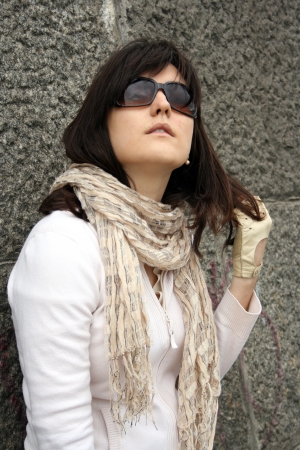Woman in sunglasses on background of stony wall. She wearing in scarf and gloves.の写真素材