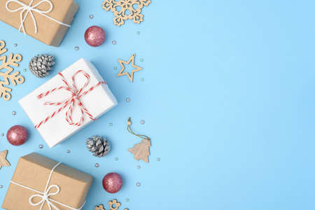 Blue background with gifts, Christmas decorations, wooden snowflakes, silver fir cones. Place for...