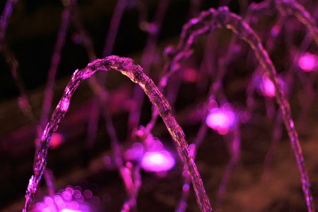 Pink water drops flowing from fontain in night park.の写真素材
