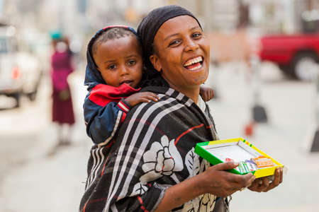 Addis Ababa, Ethiopia, January 27, 2014, Happy African woman with child selling chewing gum on the...