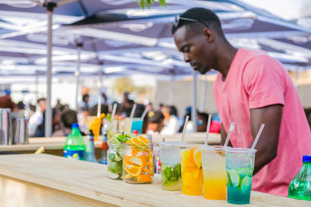 Soweto, South Africa - September 17, 2017: Diverse African vendor serving cocktail drinks at outdoor...