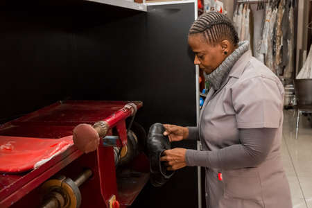 Johannesburg, South Africa - May 25, 2015: African woman working inside a Shoe repair and Dry Cleaners franchiseのeditorial素材
