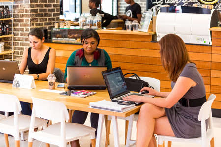 Johannesburg, South Africa - October 03 2013: Diverse Female Customers using Internet in a Coffee Shopのeditorial素材