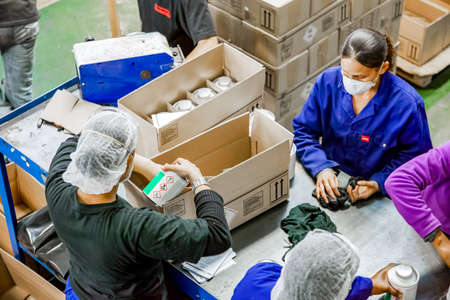 Johannesburg, South Africa - October 19, 2012: Diverse people working on an assembly line in a glue...