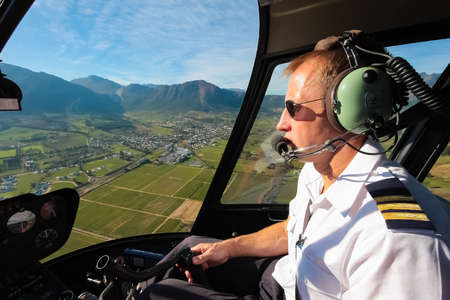 Hermanus, South Africa - July 20, 2009: Caucasian male helicopter pilot flying a R44 type chopper over rural areaのeditorial素材