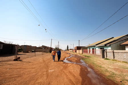 Soweto, South Africa - September 10, 2011: Two African men walking on a neighborhood dirt road in the Soweto suburbsのeditorial素材