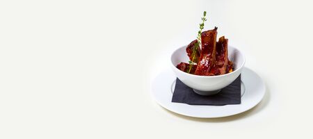 BBQ Ribs in a white bowl on a white plate on a white background isolated