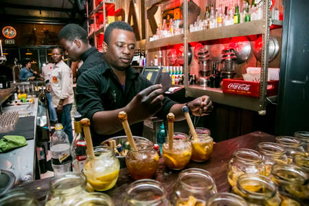 Johannesburg, South Africa - July 24, 2014: African Bartender making a Fruity cocktail at bar...