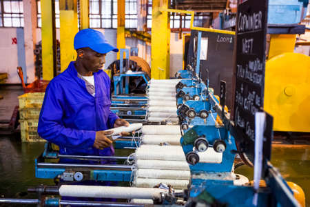 Johannesburg, South Africa - October 16, 2012: African factory worker on a copwinder weft assembly line loomのeditorial素材