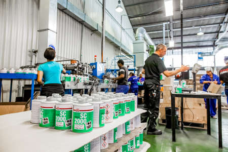 Johannesburg, South Africa - October 19, 2012: Diverse people working on an assembly line in a glue...