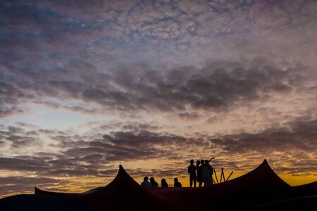 Silhouette people watching a sunset from the top of a bus at a festivalの写真素材