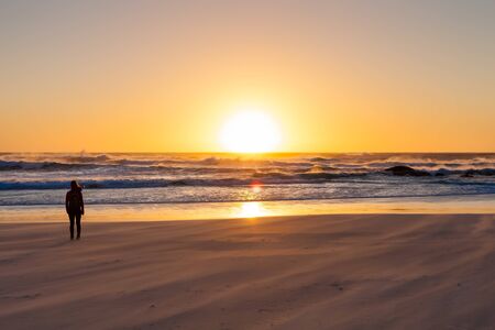 Girl watching sunset on windy beachの写真素材