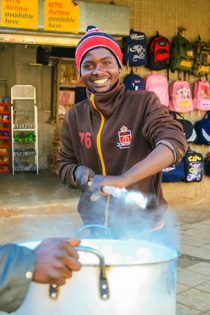 Johannesburg, South Africa, July 12, 2009, Young African man cooking Mielie Pap maize porridge on side street in urban Sowetoのeditorial素材
