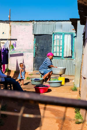 Johannesburg, South Africa, September 11, 2011, African mother and child washing clothes in Low-income Soweto neighborhoodのeditorial素材
