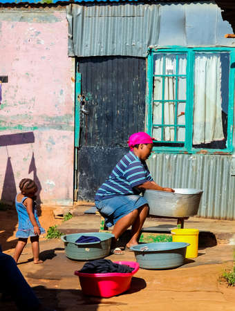 Johannesburg, South Africa, September 11, 2011, African mother and child washing clothes in Low-income Soweto neighborhoodのeditorial素材