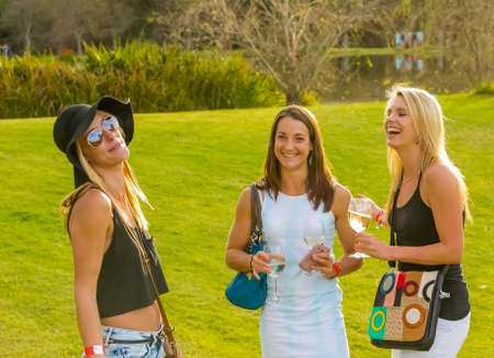 Johannesburg, South Africa, 05/10/2014,  Three young women enjoying a glass of wine and a laugh at The Winter Sculpture Fair at Nirox Sculpture Parkのeditorial素材