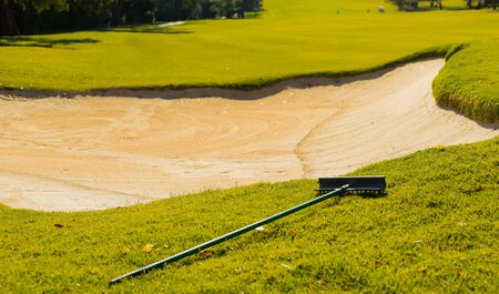 Sand Bunker Hazard and rake on Golf Course Fairway in afternoon light の写真素材