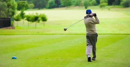Man teeing off on a golf course with a driverの写真素材