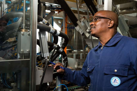 Johannesburg, South Africa - August 13, 2015: Black African male supervisor checking a machine on a packaging plant assembly lineのeditorial素材