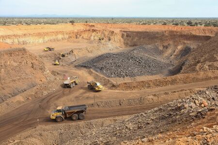 Open pit Manganese Mining - Excavator digging out ore rich rock and loading it onto rock dump trucks...